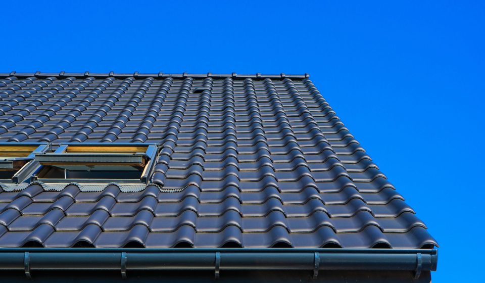 A vertical low angle closeup shot of the black roof of a building with a blue background